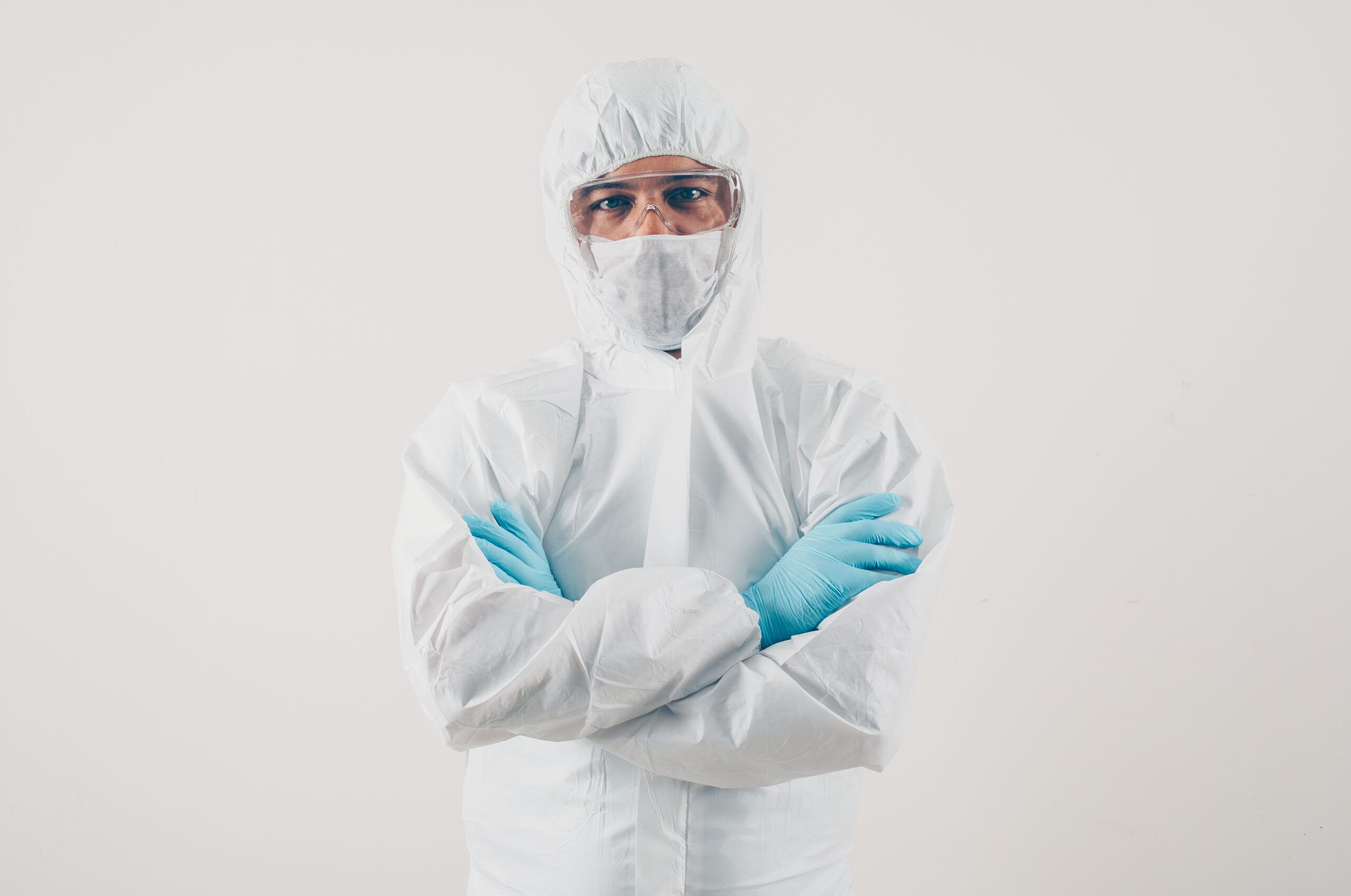 Portrait of a doctor at light background standing and looking in mask, medical gloves and protective suit coronavirus